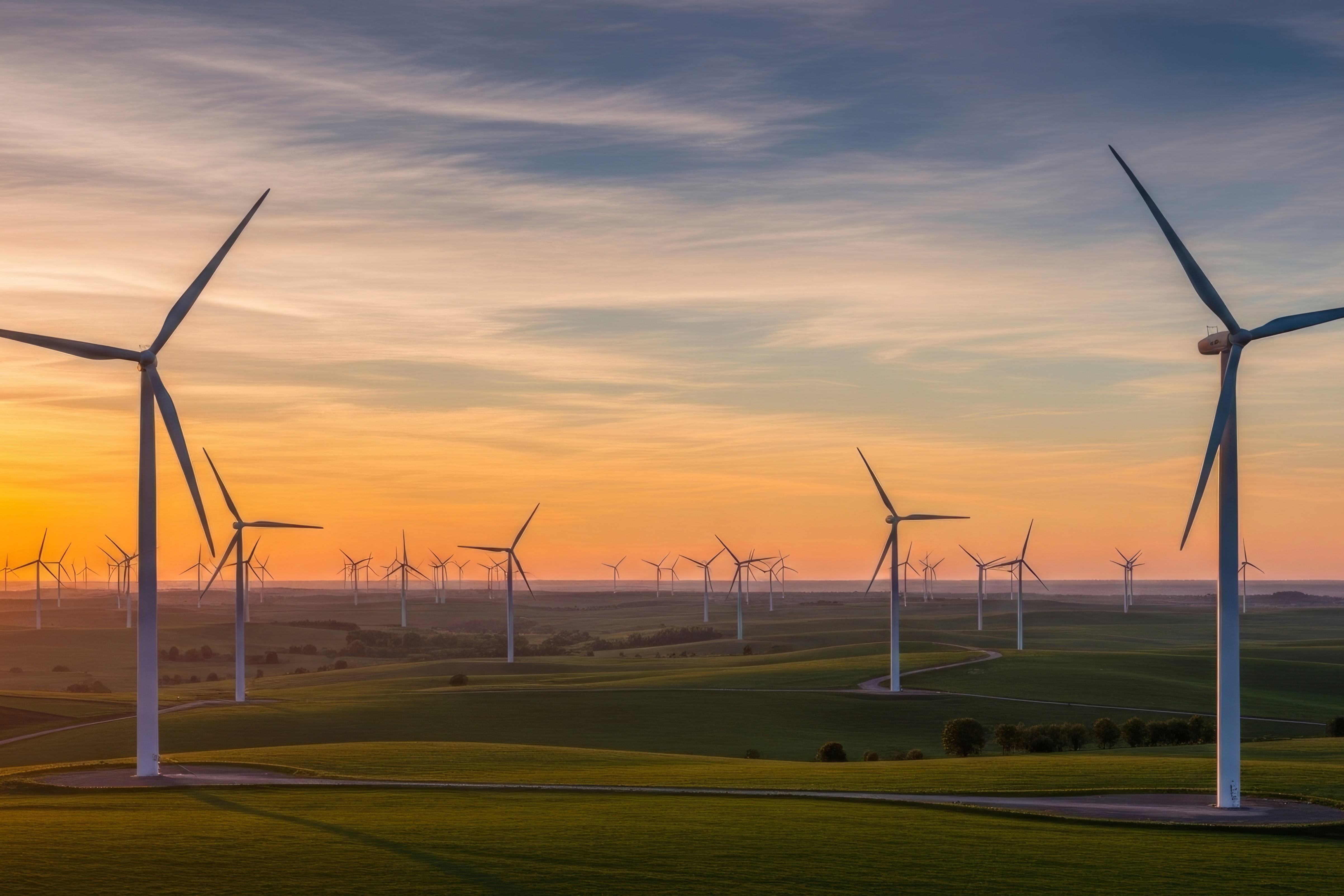 Wind turbines against sunset sky